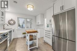 Kitchen with stainless steel appliances, decorative backsplash, white cabinets, and light stone counters - 