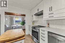 Kitchen featuring stainless steel appliances, white cabinetry, backsplash - 