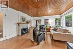 Living area featuring a stone fireplace, light wood floors, wood ceiling - 