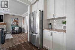 Kitchen featuring freestanding refrigerator, white cabinets, light quartz counters, crown molding, and decorative backsplash - 