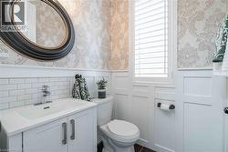 2-pc powder room featuring wallpapered walls, a wainscoted wall, vanity, and a decorative wall. - 