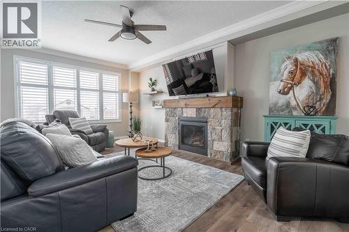 Living area with a beautiful stone fireplace complete with ornamental molding, wood finished floors, and a ceiling fan - 115 Larry Crescent, Caledonia, ON - Indoor Photo Showing Living Room With Fireplace
