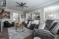 Living room with crown molding, a ceiling fan, wood finished floors, and access to stairway, planning centre and kitchen/dining areas. - 