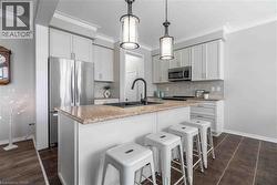 Kitchen featuring  stainless steel appliances,  pendant lighting, a kitchen island with sink, and ornamental crown molding. - 