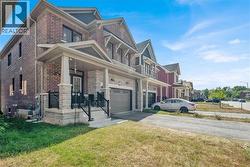 View of home's exterior featuring covered porch, an attached garage, driveway, a yard, and brick siding - 