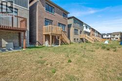 Rear view of house with brick siding, a lawn, and a deck - 