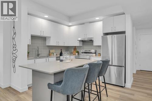Quartz countertop island with space for seating - photos are of our showhome - 1057 Frost Road Unit# 317, Kelowna, BC - Indoor Photo Showing Kitchen With Stainless Steel Kitchen With Upgraded Kitchen