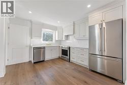 Kitchen featuring appliances with stainless steel finishes, white cabinetry, light wood-style floors, recessed lighting, and tasteful backsplash - 