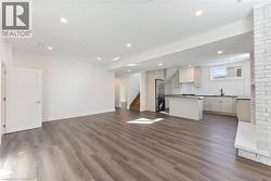 Unfurnished living room with stairs, dark wood-style floors, and recessed lighting - 