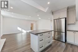 Kitchen with dark countertops, freestanding refrigerator, dark wood finished floors, open floor plan, and recessed lighting - 