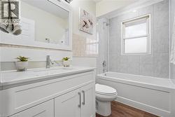 Full bath featuring shower / tub combination, vanity, and dark wood-style floors - 