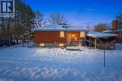 Snow covered back of property with brick siding and a wooden deck - 