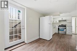 Kitchen with freestanding refrigerator, electric stove, white cabinets, light countertops, and dark wood-type flooring - 
