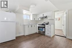 Kitchen with freestanding refrigerator, electric stove, light countertops, and dark wood-style flooring - 