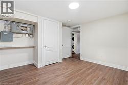 Unfurnished bedroom with electric panel, wood finished floors, and estacked washer and dryer - 