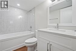 Full bathroom with shower / bath combination, vanity, dark wood-style flooring, and recessed lighting - 
