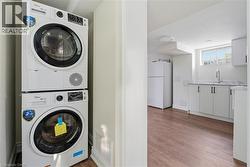 Laundry area with wood finished floors and stacked washer / dryer - 