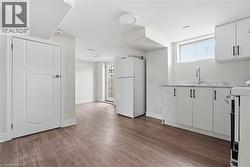 Kitchen with white appliances, white cabinets, and dark wood-style flooring - 