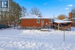 Snow covered back of property featuring brick siding and a deck - 