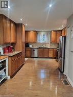 Kitchen with brown cabinets, light wood finished floors, appliances with stainless steel finishes, and backsplash - 