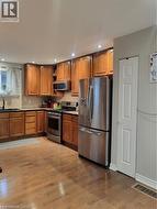 Kitchen with appliances with stainless steel finishes, brown cabinetry, wood finished floors, open shelves, and recessed lighting - 