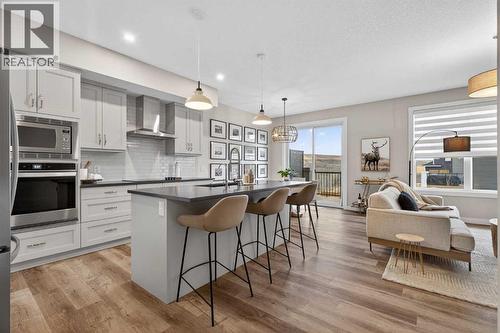 Open concept kitchen and living room with large island, and access to the private backyard - 307 Precedence Hill, Cochrane, AB - Indoor Photo Showing Kitchen With Upgraded Kitchen