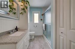 Full bath featuring wainscoting, vanity, a stall shower, and light wood-type flooring - 