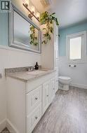 Bathroom with wainscoting, vanity, and light wood-style flooring - 