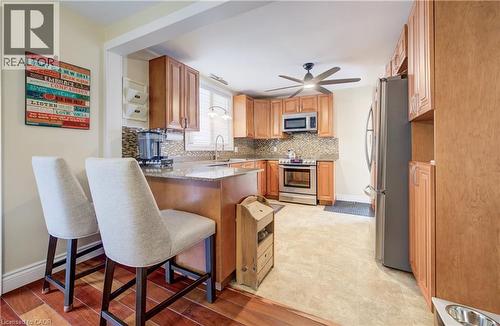 Kitchen featuring stainless steel appliances, a kitchen breakfast bar, light stone countertops, decorative backsplash, and a peninsula - 1170 Union Street, Kitchener, ON - Indoor