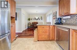 Kitchen featuring stainless steel appliances, a peninsula, light stone countertops, wood finish cabinets, and pendant lighting - 