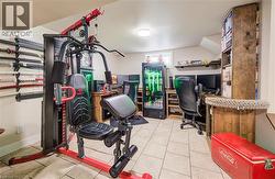 Exercise room featuring light tile patterned flooring and baseboards - 