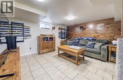 Living room featuring wooden walls, an accent wall, and light tile patterned floors - 
