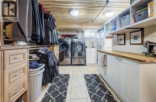 Laundry room with washing machine and dryer, cabinet space, wooden ceiling, and light tile patterned floors - 1170 Union Street, Kitchener, ON - Indoor Photo Showing Laundry Room