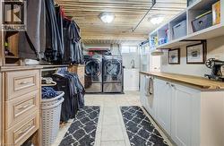 Laundry room with washing machine and dryer, cabinet space, wooden ceiling, and light tile patterned floors - 