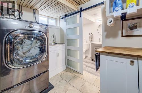Laundry area featuring a barn door, washer / dryer, wood ceiling, and light tile patterned flooring - 1170 Union Street, Kitchener, ON - Indoor Photo Showing Laundry Room
