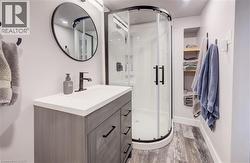 Full bathroom with vanity, a shower stall, and light wood-style floors - 