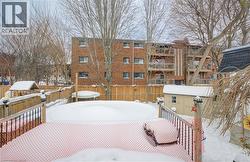 Snow covered deck featuring a storage unit and a fenced backyard - 
