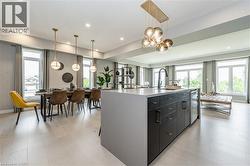 Kitchen with dark cabinets, decorative light fixtures, a kitchen island with sink, plenty of natural light, and recessed lighting - 