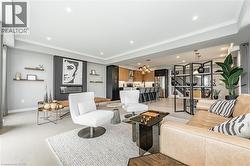 Living room featuring a chandelier, recessed lighting, stairway, crown molding, and a glass covered fireplace - 