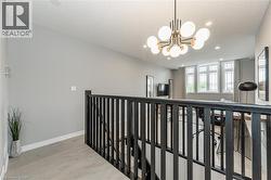 Hall featuring light wood-style flooring, a chandelier, recessed lighting, and an upstairs landing - 