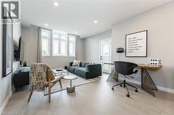 Living room featuring light wood finished floors, a desk, and recessed lighting - 