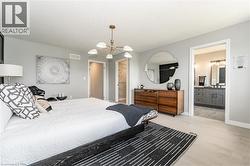Bedroom with connected bathroom, light wood-style flooring, and a chandelier - 