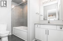 Bathroom with vanity, shower / bath combination, and dark tile patterned floors - 