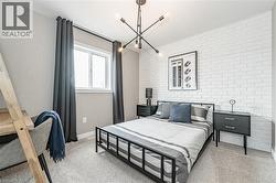 Bedroom featuring brick wall, light carpet, and a chandelier - 