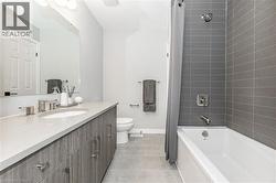Full bath with vanity, shower / tub combo with curtain, and light tile patterned floors - 