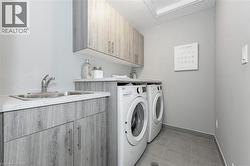 Washroom with light tile patterned floors, cabinet space, and washer and dryer - 