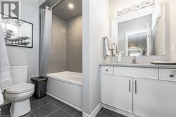 Full bath featuring vanity, shower / tub combo, and dark tile patterned flooring - 