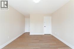 Unfurnished bedroom with light wood finished floors and baseboards - 