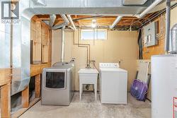 Washroom with water heater, concrete floors, washing machine and clothes dryer, and electric panel - 