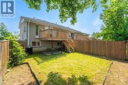 Back of property featuring a fenced backyard, stairway, brick siding, and a wooden deck - 
